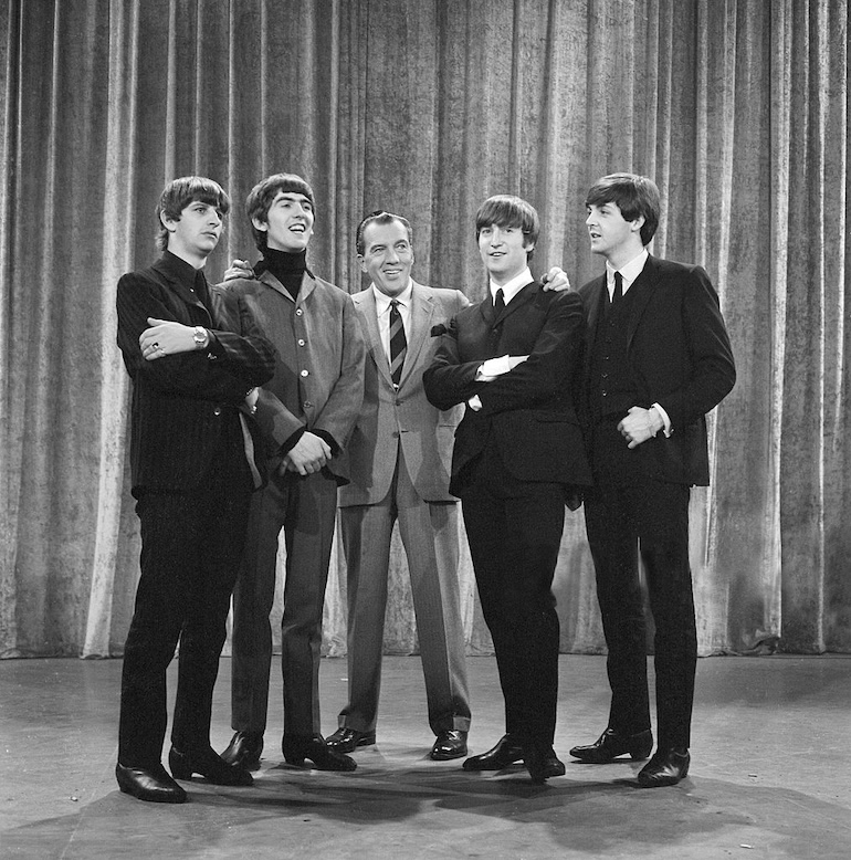 Photo of The Beatles with Ed Sullivan in February 1964. Photo Credit: © Public Domain via Wikimedia Commons. 